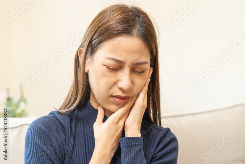 Closing eyes asian young woman touching cheek, face expression from toothache, tooth decay or sensitivity, Having tooth or teeth problem or inflammation, suffering from health. Sensitive teeth people