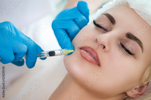 Plastic Surgery Concepts. Closeup Beautician Hands Doing Facial Skin Lifting Injection To Woman s Lips While Female Posing With Closed Eyes and Receiving Beauty Procedure Indoors.