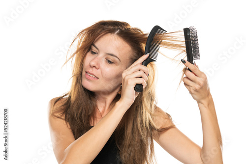 portrait of a young woman brushing her messy long hair on a white background