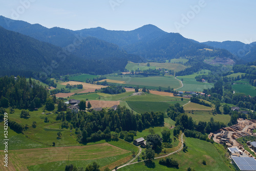 View green meadow and farm fields, forest in the mountains