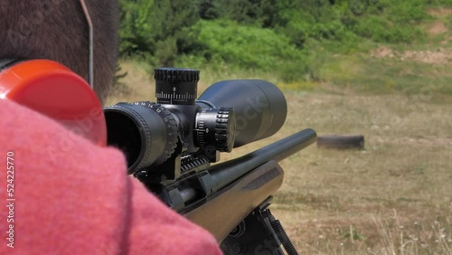 Footage of a sniper shooter preparing himself to shoot towards a target in the distance