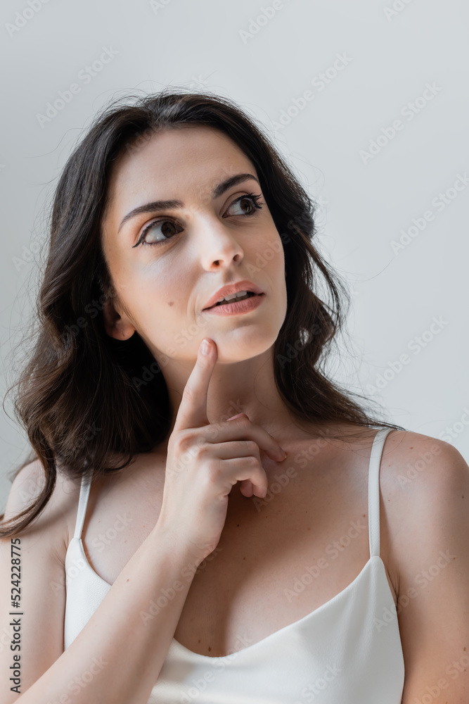 Pensive young woman looking away isolated on grey. Pensive young woman looking away isolated on grey.