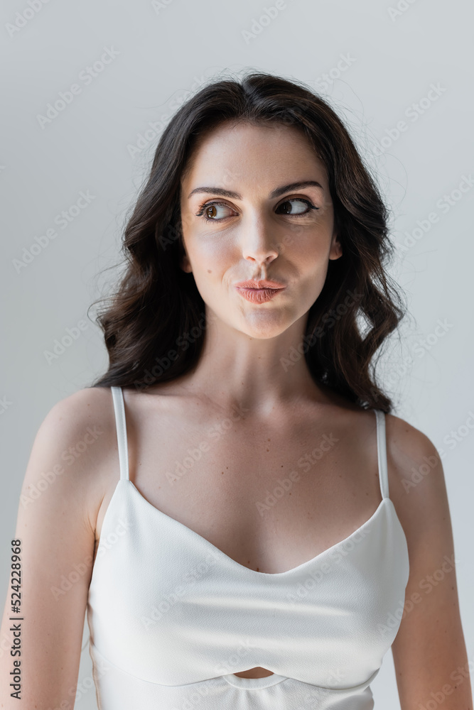 Portrait of sly woman in white top isolated on grey. Portrait of sly woman in white top isolated on grey.
