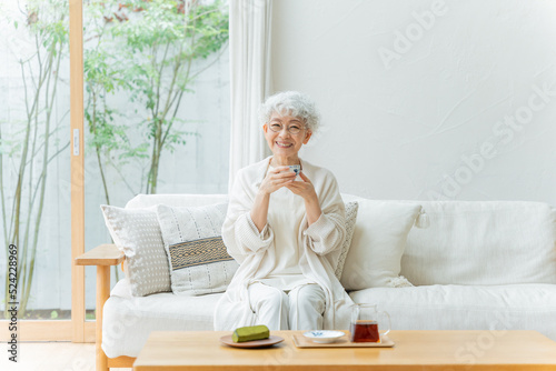 お茶を飲んでリラックスするシニア女性（ティータイム・お菓子・休憩） photo
