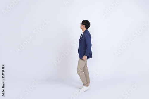 Full length portrait of Asian businessman in casual dress looking at copy space for text isolated on white background
