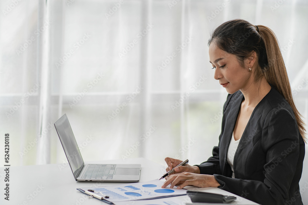 Asian business woman Use a laptop computer and work with the calculator documents on the desk. plan to analyze financial reports Invest in an office business plan Asian business woman Use a laptop computer and work with the calculator documents on the desk. plan to analyze financial reports Invest in an office business plan