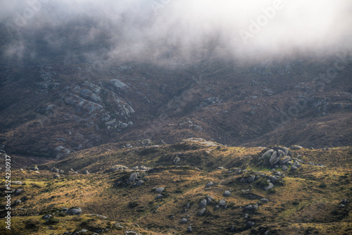 The fog dissipates and reveals a landscape of rocks and grasses in the Xistral