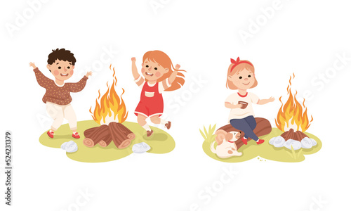 Little children camping around bonfire. Cute kids jumping by fire and drinking tea cartoon vector illustration