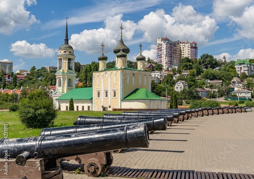 Cannons on Admiralteyskaya embankment. In the background is Assumption Admiralty Church and residential area. Historical place in cradle of Russian Navy. Voronezh, Russia - July 30, 2022.