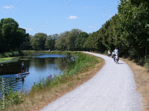 A man on a stand-up paddle on a small canal. July 2022, Blain, France.  photo