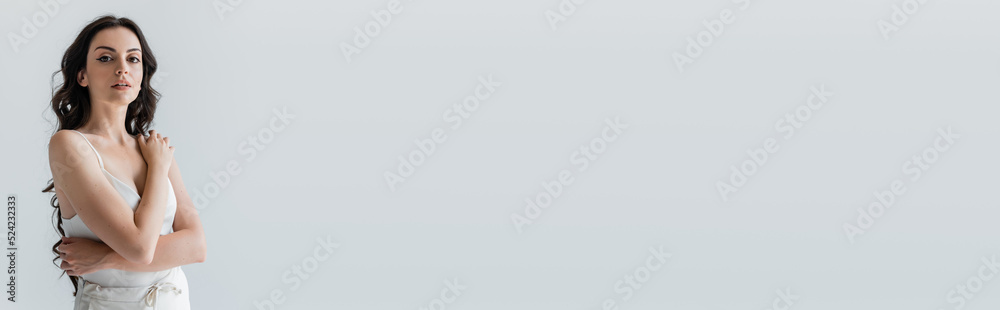 Young brunette model looking at camera isolated on grey, banner. Young brunette model looking at camera isolated on grey, banner.