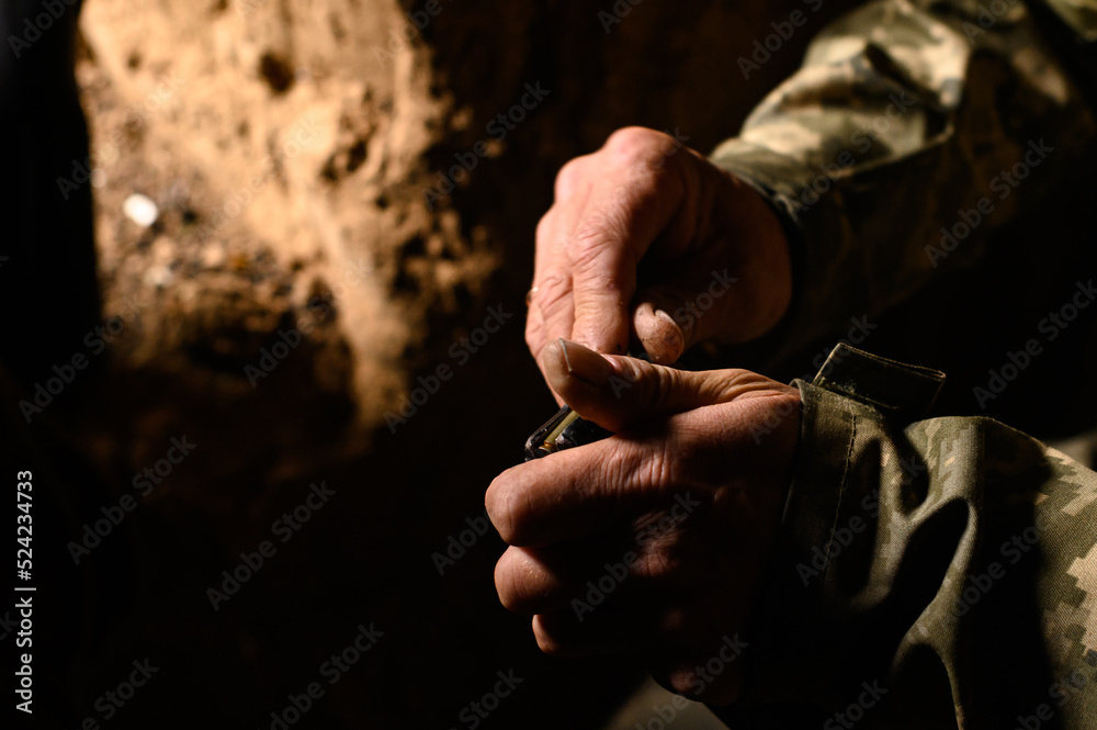 Filling the magazine with combat military assault rifles AK 74, a soldier in a trench holding ammunition for a machine gun.