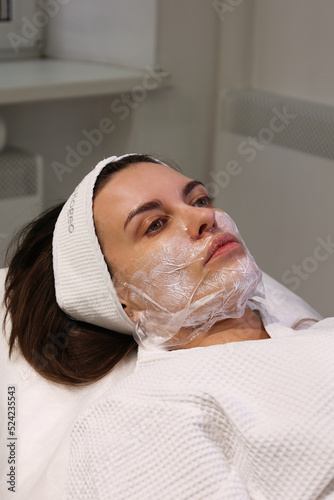 Close up of young clean woman face with cream with anesthesia. Patient's face macro. Biorevitalization or thread lifting procedure. Portrait of woman in beauty clinic with doctor beautician.
