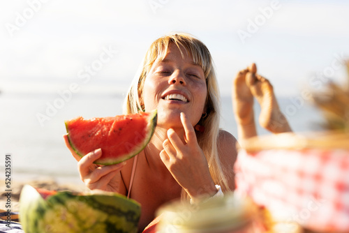  Cheerful young woman enjoy at tropical sand beach. Girl eating a fruit photo