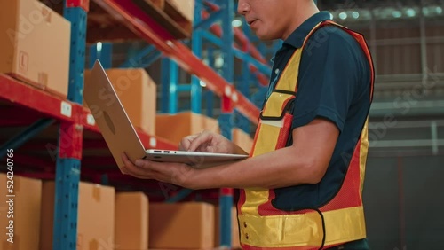 Wallpaper Mural Young asian male worker wearing helmet using laptop in modern warehouse. Torontodigital.ca