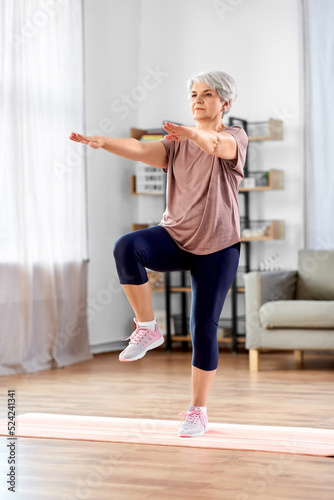 sport  fitness and healthy lifestyle concept - smiling senior woman exercising on mat at home