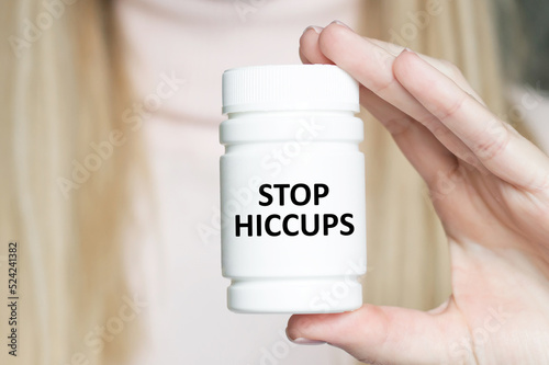 STOP HICCUPS inscription on a white jar with medicine in the doctor's hand, medical concept