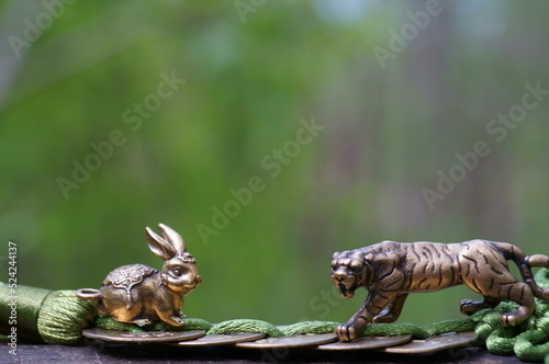 Metal rabbit and tiger figurine with Chinese coins. An esoteric symbol.