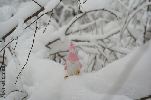 A toy gnome on skis in the winter forest. Christmas figurines.