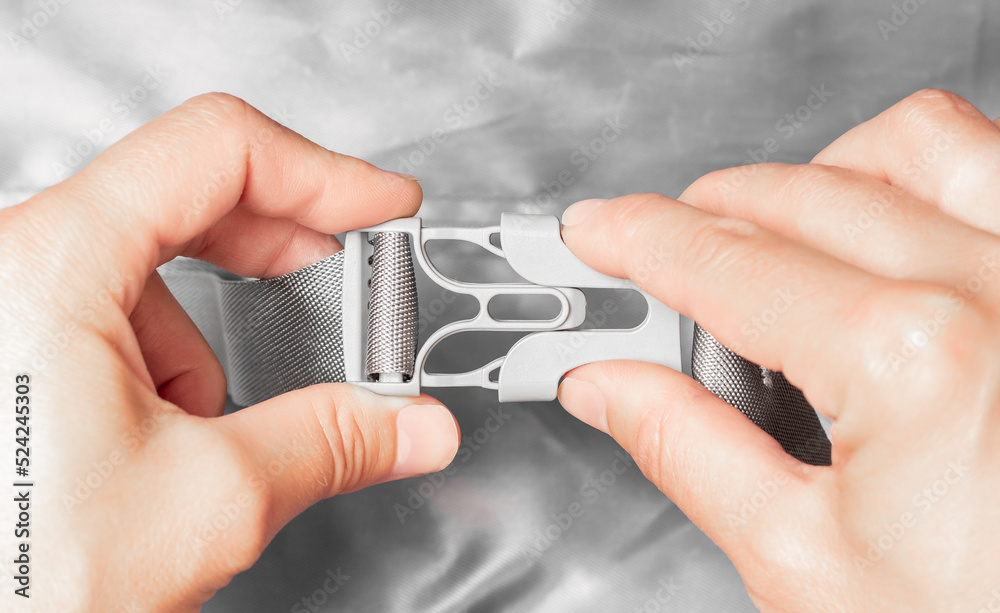 Fototapeta premium Gray plastic buckle. Fasten the plastic clip. Women's hands fasten a plastic buckle.
