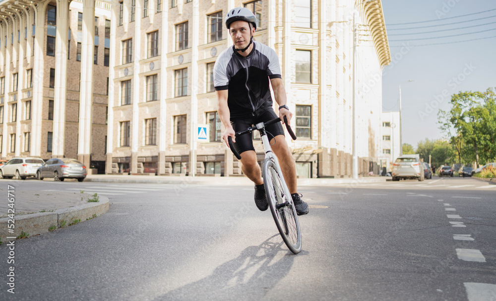 A male athlete on a road bike in a helmet rides in cycling clothes. Eco transport in the city
