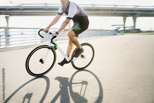 A photo in motion, a man on a road bike in a helmet riding in cycling clothes for training