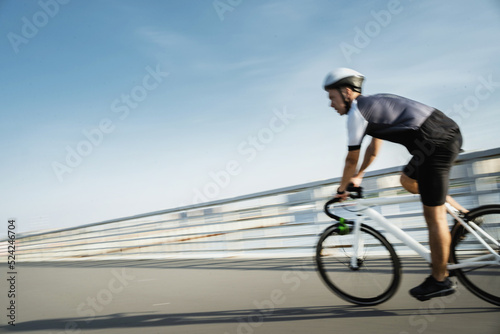 In motion blurred, a male athlete in gear rides a bike for highway training