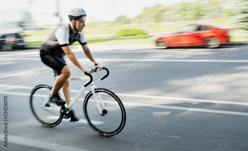 Blurry photo in motion, Male athlete in gear riding bike for highway workout