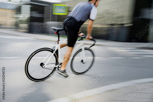 A blurry photo in motion, a man on a road bike in a helmet riding in cycling clothes. Eco transport in the city