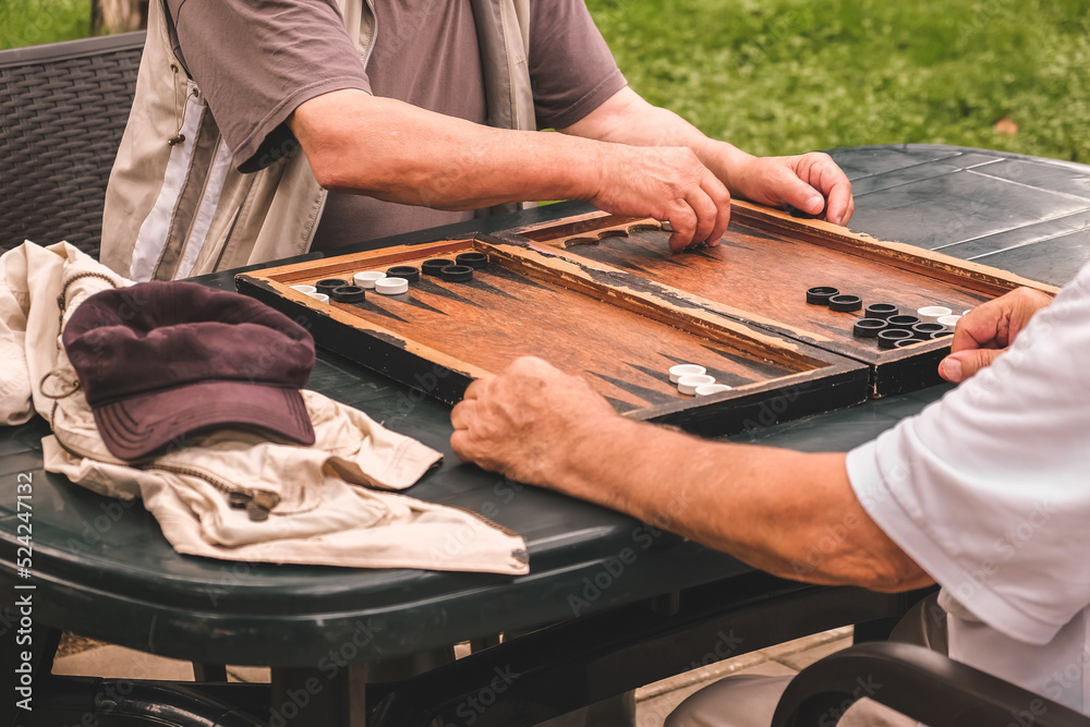 Board game of backgammon.Two old adult men playing backgammon in