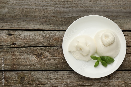 Delicious burrata cheese with basil on wooden table, top view. Space for text