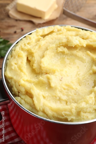 Red pot with tasty mashed potatoes on table, closeup