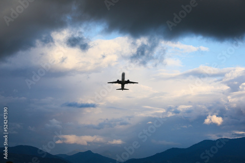 Modern white airplane flying in sky with clouds, low angle view © New Africa
