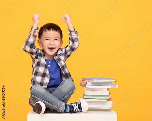  Happy kid sitting with books isolated on yellow background