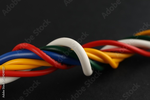 Many twisted electrical cables on black background, closeup