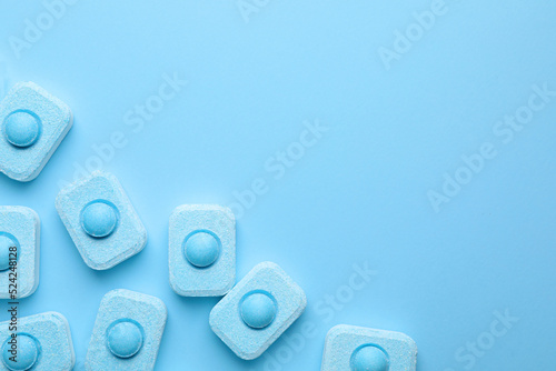 Water softener tablets on light blue background, flat lay. Space for text photo