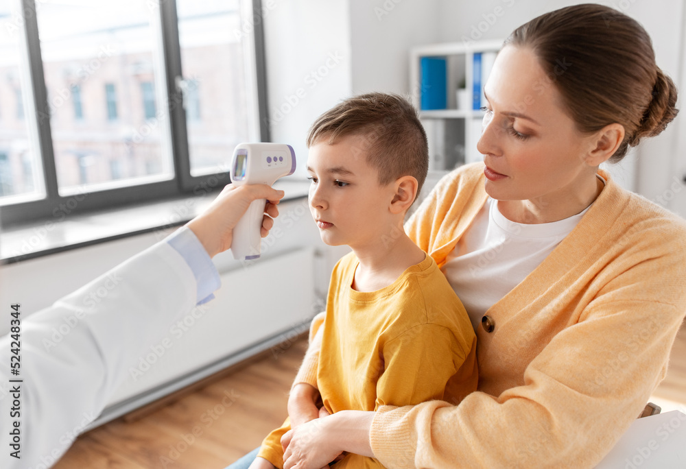 medicine, healthcare and pediatry concept - mother with sick little son and doctor measuring temperature with infrared forehead thermometer at clinic medicine, healthcare and pediatry concept - mother with sick little son and doctor measuring temperature with infrared forehead thermometer at clinic
