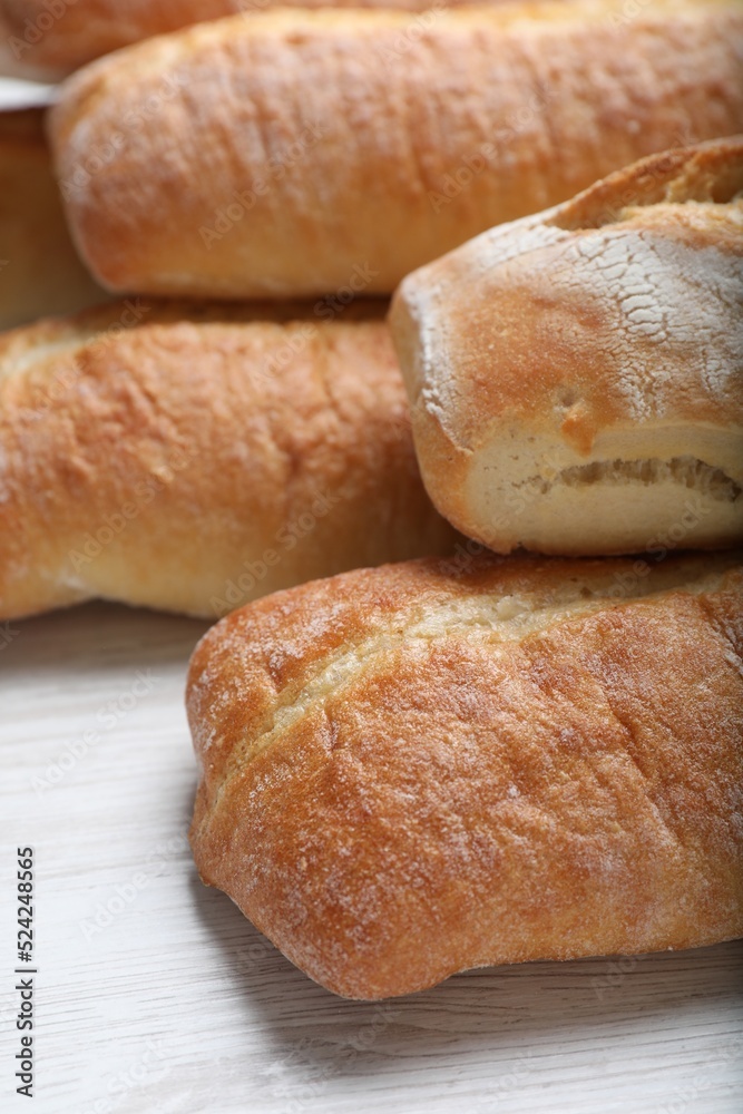 Tasty baguettes on white wooden table, closeup