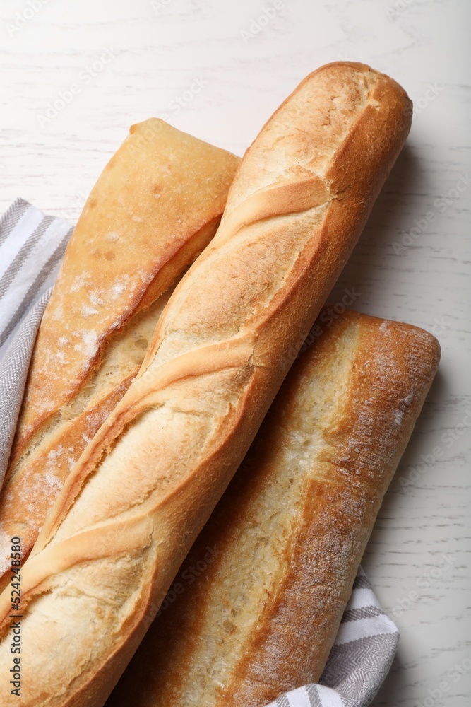 Different tasty baguettes on white wooden table, flat lay