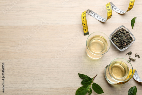 Flat lay composition with diet herbal tea and measuring tape on wooden background, space for text