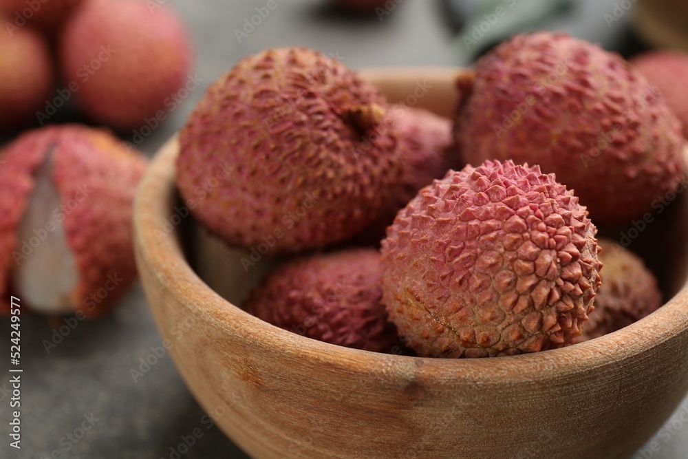 Fresh ripe lychee fruits in wooden bowl on table, closeup Fresh ripe lychee fruits in wooden bowl on table, closeup