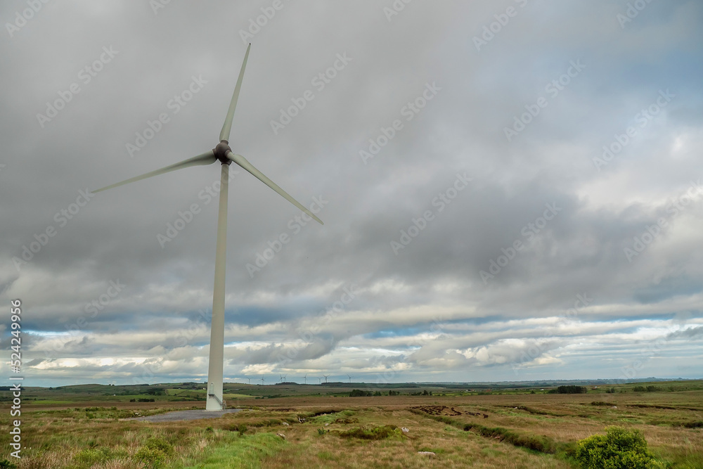 Wind turbine in a big open field. County Galway, Ireland. Production of clean electric energy. Dark dramatic sky. Nobody. Green renewable source of power. Wind turbine in a big open field. County Galway, Ireland. Production of clean electric energy. Dark dramatic sky. Nobody. Green renewable source of power.