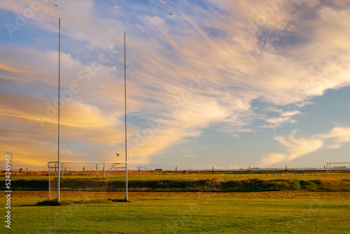 Tall goal posts for Irish National sports in a field of a park at sunrise. Rugby, hurling, camogie and Gaelic football training ground. Nobody. Calm warm color. Dramatic sky. © mark_gusev