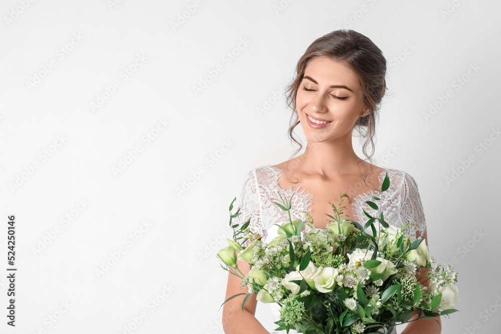 Young bride wearing wedding dress with beautiful bouquet on light background. Space for text Young bride wearing wedding dress with beautiful bouquet on light background. Space for text