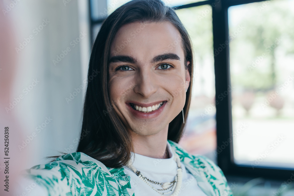Portrait of cheerful queer designer looking at camera in creative agency. Portrait of cheerful queer designer looking at camera in creative agency.