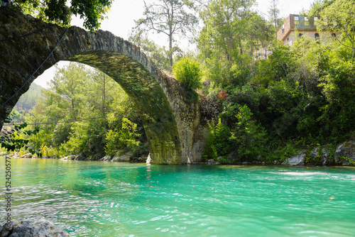 Ancient roman bridge on Dim river in Turkey. Clear turquoise water and green nature. 