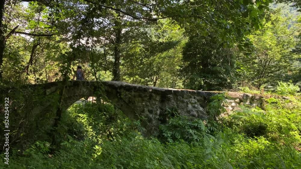 The stone arch bridge in Mirveti with female tourist posing for photo. Adjara travel destination outdoors The stone arch bridge in Mirveti with female tourist posing for photo. Adjara travel destination outdoors