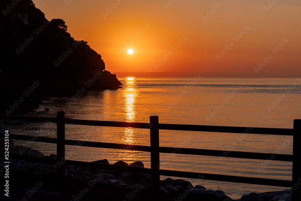 Beautiful view of orange sunset seascape with rocks in Italy. Tropical colourful sunrise landscape. Nature landscape. Tropical island coast