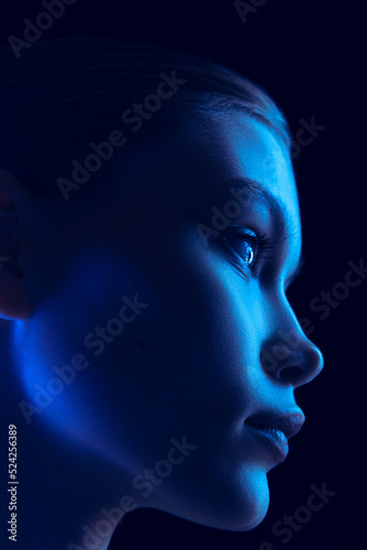 Marvelous night. Closeup portrait of young woman in neon light on dark background. Monochrome. Cyberpunk style, beauty, cosmetics concept.