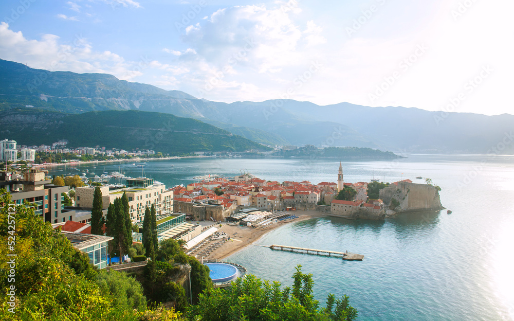 Landscape aerial view on roofs of old historical town of Budva and sea bay, mountains and forests of Montenegro, on background of blue sky